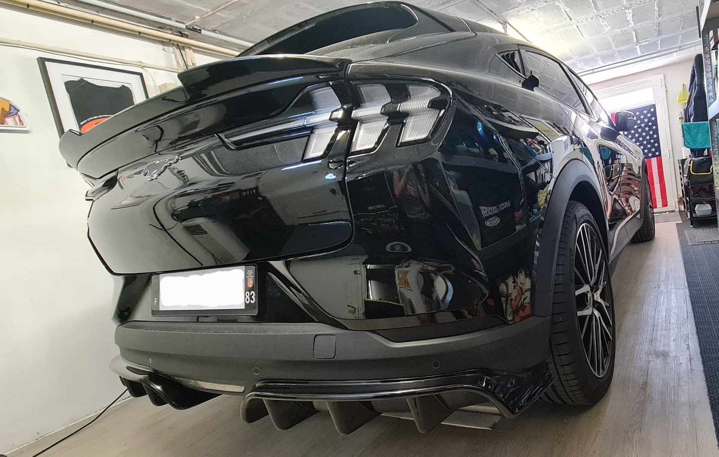 Rear diffuser on black 2021-2025 Mustang Mach-E in garage with American flag background