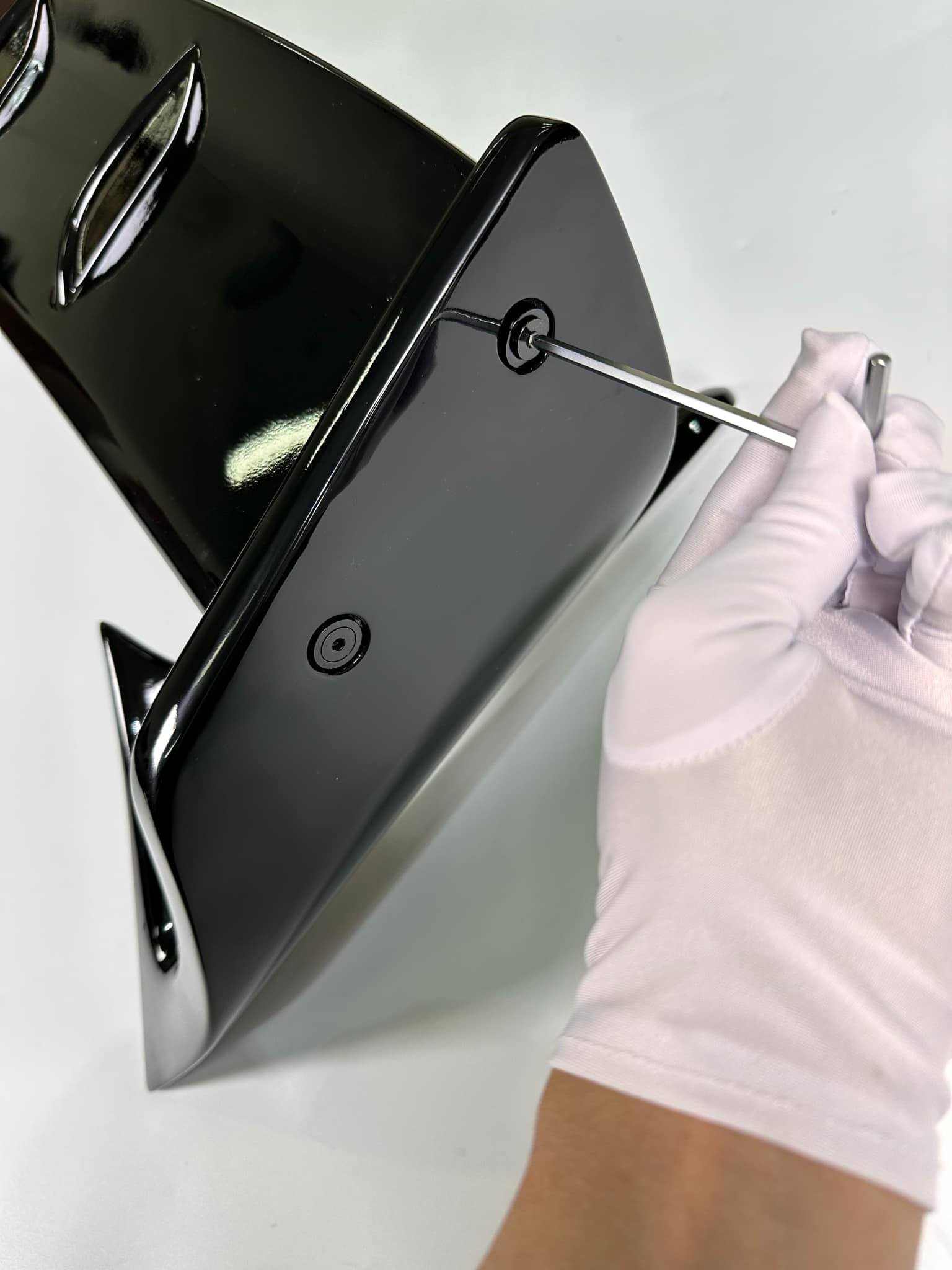 Close-up of person wearing white gloves installing a black Rally Wing Spoiler for Ford Mustang Mach-E using a screwdriver
