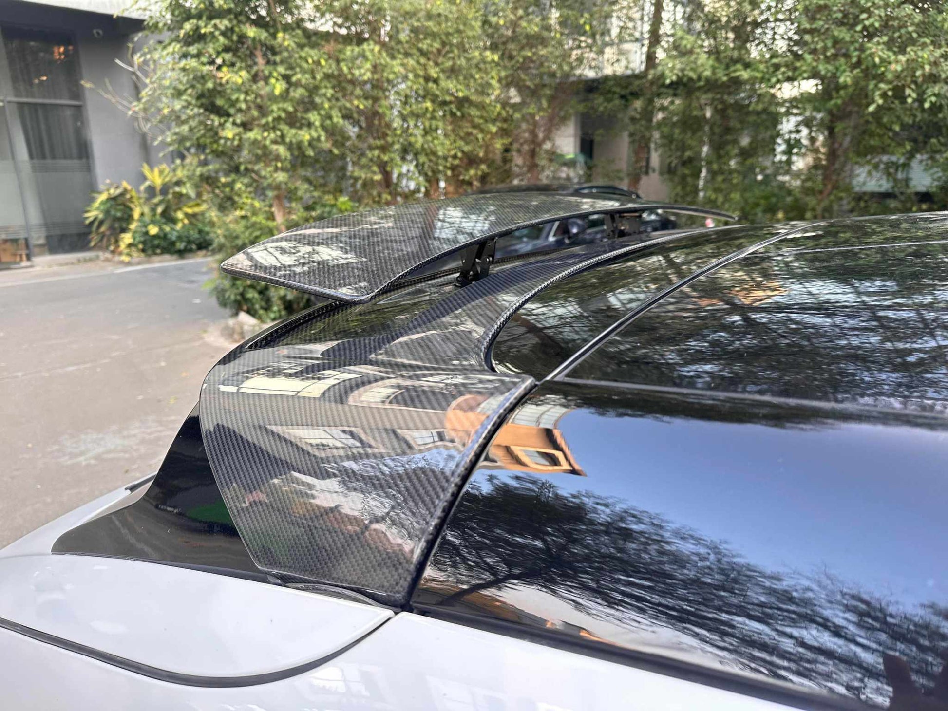 Close-up of retractable carbon fiber spoiler installed on a Mustang Mach-E roof, partially raised for aerodynamic enhancement.