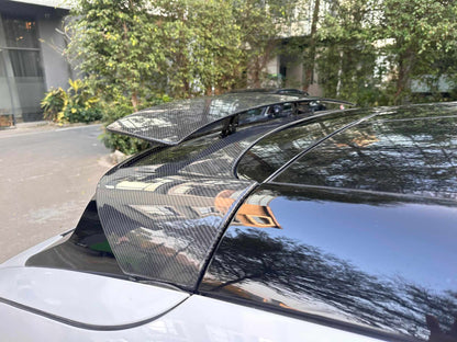 Close-up of retractable carbon fiber spoiler installed on a Mustang Mach-E roof, partially raised for aerodynamic enhancement.