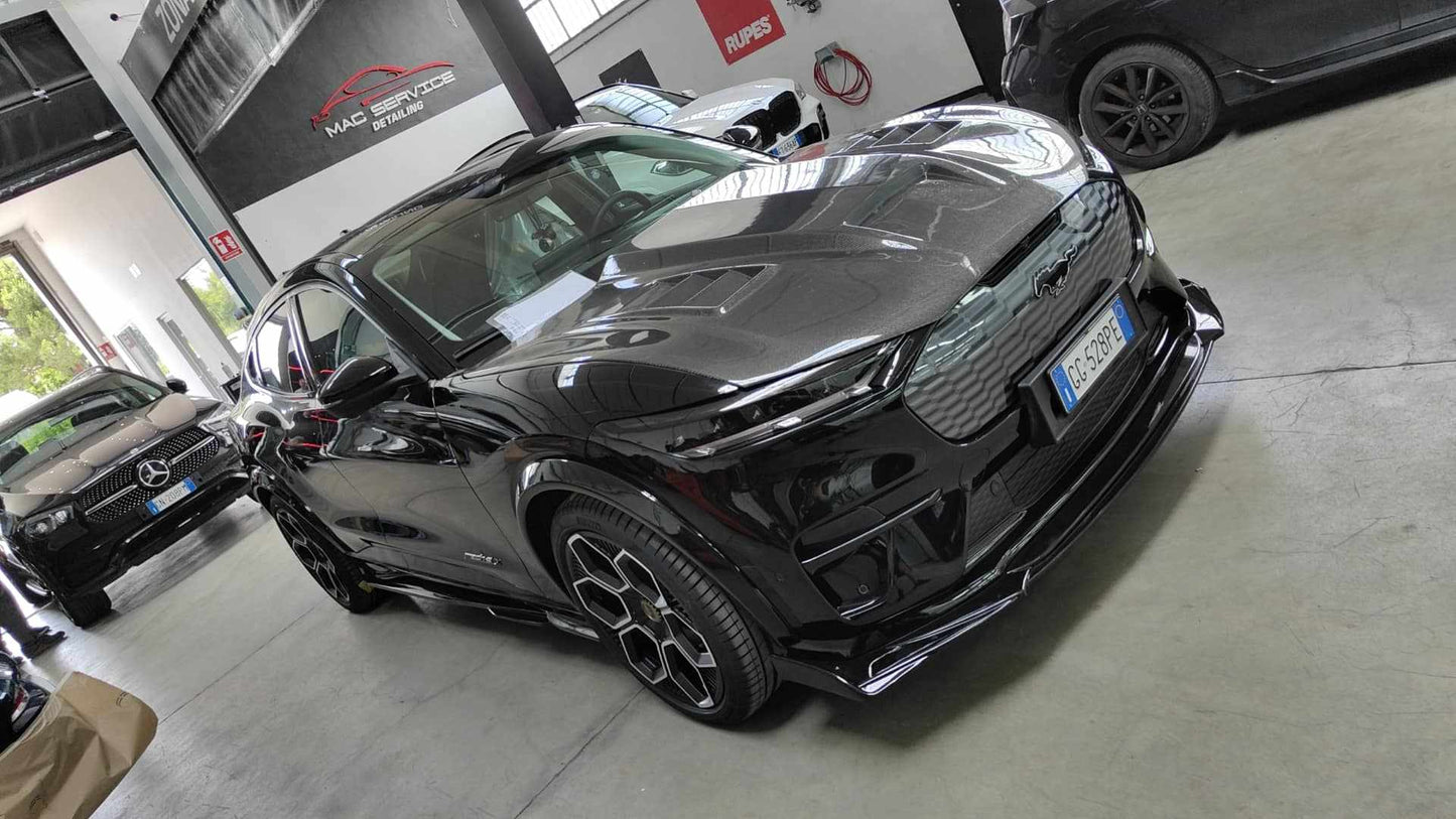 Black Ford Mustang Mach-E with aftermarket Shelby GT550 style fiber hood in a garage setting